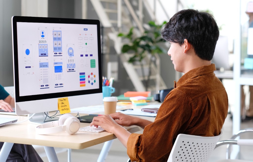 A designer working through website wireframes on a desktop monitor